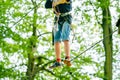 School boy in forest adventure park. Acitve child, kid in helmet climbs on high rope trail. Agility skills and climbing