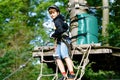 School boy in forest adventure park. Acitve child, kid in helmet climbs on high rope trail. Agility skills and climbing