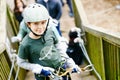 School boy in forest adventure park. Acitve child, kid in helmet climbs on high rope trail. Agility skills and climbing