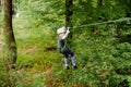 School boy in forest adventure park. Acitve child, kid in helmet climbs on high rope trail. Agility skills and climbing