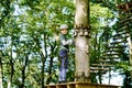 School boy in forest adventure park. Acitve child, kid in helmet climbs on high rope trail. Agility skills and climbing