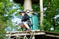 School boy in forest adventure park. Acitve child, kid in helmet climbs on high rope trail. Agility skills and climbing