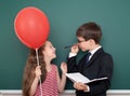 School boy and girl child with balloon on chalkboard background having fun Royalty Free Stock Photo