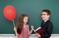 School boy and girl child with balloon on chalkboard background having fun Royalty Free Stock Photo
