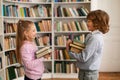 School boy and girl holding stack of books and talking with each other standing in library, side view Royalty Free Stock Photo