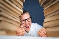 School boy in glasses sitting between two piles of books and loo Royalty Free Stock Photo