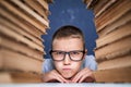 School boy in glasses sitting between two piles of books and loo Royalty Free Stock Photo