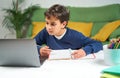 School boy having online classes while sitting at home in quarantine, using laptop Royalty Free Stock Photo