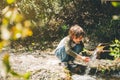 School boy kid drinking water from the mountain creek. Tourist child wearing casual clothes making a sip of mountain Royalty Free Stock Photo