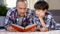 School boy listening to dad reading exciting adventure book, love to literature