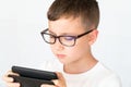 School boy looks handsome smartphone video, in glasses, unhappy Royalty Free Stock Photo