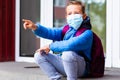 School boy resting outdoors. Bored little student look aside.boy wears protective mask pointing with finger somewhere Royalty Free Stock Photo