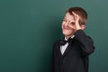 School boy show ok sign, portrait near green blank chalkboard background, dressed in classic black suit, one pupil, education conc Royalty Free Stock Photo