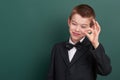 School boy show ok sign, portrait near green blank chalkboard background, dressed in classic black suit, one pupil, education conc Royalty Free Stock Photo