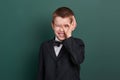 School boy show ok sign, portrait near green blank chalkboard background, dressed in classic black suit, one pupil, education conc Royalty Free Stock Photo