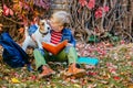 School boy sitting on bright colorful leaves kissing and hugging his dog in the fall autumn park, outdoor. Happy child with puppy Royalty Free Stock Photo