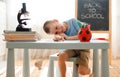 School boy sitting at home classroom lying desk filled with books training material schoolchild sleeping lazy bored Royalty Free Stock Photo