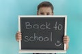 school boy stands behind blackboard with inscription back to school made with piece of chalk. Royalty Free Stock Photo