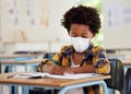 School boy, student and learning while writing and working in his book inside a classroom with a mask due to covid Royalty Free Stock Photo