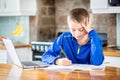 School boy studying at home doing distance learning and online education