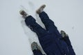 School boy in winter clothes playing in the snow. sometimes he lies on the ground on his back and rests. they risk getting cold an