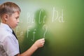 School boy writes English alphabet with chalk on blackboard Royalty Free Stock Photo