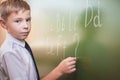 School boy writes English alphabet with chalk on blackboard Royalty Free Stock Photo