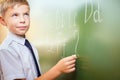 School boy writes English alphabet with chalk on blackboard