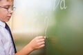 School boy writes English alphabet with chalk on blackboard Royalty Free Stock Photo