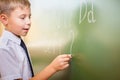 School boy writes English alphabet with chalk on blackboard Royalty Free Stock Photo