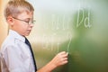 School boy writes English alphabet with chalk on blackboard Royalty Free Stock Photo