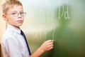 School boy writes English alphabet with chalk on blackboard Royalty Free Stock Photo