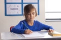 In school, boy writing in notebook at desk, focusing on her work Royalty Free Stock Photo