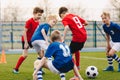 School boys playing football game. Young players kicking soccer ball on sports grass pitch Royalty Free Stock Photo