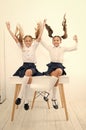 School break concept. Schoolgirls cute pony tails hairstyle sit on desk. Best friends free having fun play with hair
