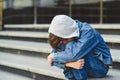 School bullying concept. Kid boy sitting at stair, covering his face. Sad young schoolboy outside school. Negative emotion, Royalty Free Stock Photo