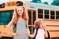 School bus and Happy Children. Portrait of happy little brother and sister standing together in front of school bus. Royalty Free Stock Photo