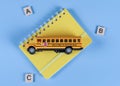 School bus and notebook on blue. Royalty Free Stock Photo