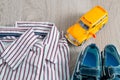 School bus toy near shirts and blue boat shoes on grey wooden background. Boy outfit. Close up. Royalty Free Stock Photo