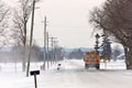 School Bus Travelling Down a Country Road with Snowdrifts and Blowing Snow in Winter