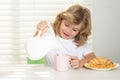 School chil pouring whole cows milk for breakfast. Funny kid boy having breakfast. Milk, vegetables and fruits healthy Royalty Free Stock Photo