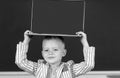 School child holding laptop on head using digital pc laptop in class. Portrait of funny pupil of primary school study Royalty Free Stock Photo