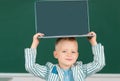 School child holding laptop on head using digital pc laptop in class. Portrait of funny pupil of primary school study Royalty Free Stock Photo