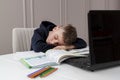 School child studying at home, tired sleep and lying on laptop while doing school homework. Distance learning online education.