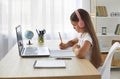 School child sitting at desk with laptop computer, studying online and writing in notebook Royalty Free Stock Photo