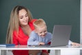 School child using laptop. Elementary school teacher and pupil in classroom. Mother and son together using computer Royalty Free Stock Photo
