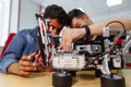 Mixed Racial group of School children controlling robotic machine with remote control together teacher. Creative kids