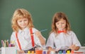 School children drawing a colorful pictures with pencil crayons in classroom. Portrait of cute pupils enjoying art and Royalty Free Stock Photo