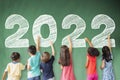 School children drawing 2022 new year on the chalkboard