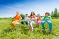 School children hold notebooks and sit on chairs